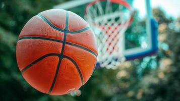 närbild av ett orange basketboll nära de ring och netto i de utomhus- domstol miljö foto