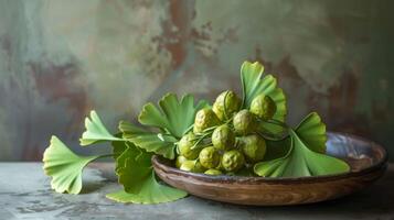 gingko nötter och löv i en trä- skål på en texturerad tabell med naturlig grön toner foto