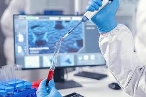 medicinsk forskare droppande blod in i en testa rör från en mikropipett. läkare arbetssätt med olika bakterie och vävnad, farmaceutisk forskning för antibiotika mot covid19. foto