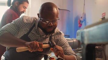 afrikansk amerikan tillverkare formning rå timmer använder sig av mejsel och hammare, skapande trä konst, framställning exakt skärsår. konstnär framställning handgjort trä skulpturer, gravyr virke med verktyg, kamera b stänga upp foto