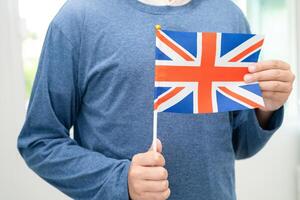 lära sig engelsk språk, asiatisk Tonårs studerande håll Storbritannien flagga i kurs på skola. foto