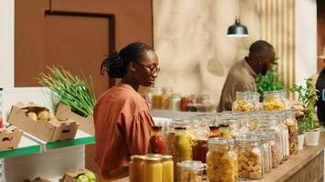 afrikansk amerikan klient undersöker bio hemlagad bulk Produkter, ser till köpa naturlig etiskt kommer från mat alternativ för friska näring. kvinna handla för varor på noll avfall Lagra. kamera 1. foto