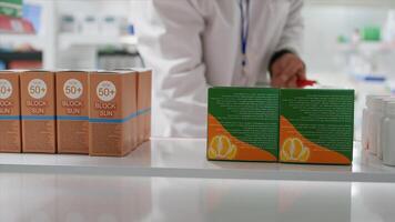 pOV av apotekare tar näringsmässiga vitaminer lådor från hyllor, byter ut dem med Övrig medicin. anställd ordna om farmaceutisk Produkter i sjukvård anläggningen. stativ skott. foto