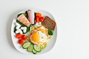 friterad ägg för frukost med grönsaker på en vit tallrik. vikt förlust mat, många vitaminer, keto menyer eller sallader. tjänande på de tabell, vit bakgrund, fri Plats för text. Nej människor foto