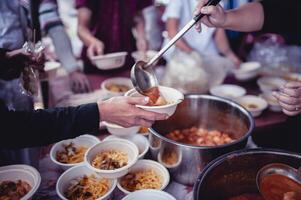 de hand av de vandrare sträcker sig till motta mat från donationer. med volontärer ösa mat. de aning av portion med hunger foto