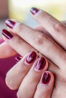 närbild av en kvinnas finger med henne naglar målad röd. foto