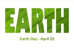 text jord dag april 22 på de bakgrund av lilja av de dal blad. jord dag begrepp, skydd av de planet från förorening och förbättring av miljö- ekologi. foto