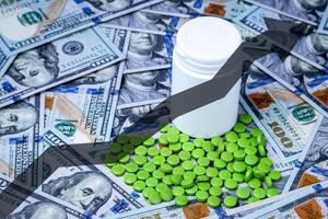 grön piller på de bakgrund av ett hundra dollar räkningar. foto