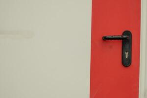 svart dörr hantera mot en vit bakgrund med en bred röd rand foto