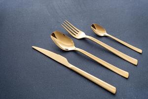 uppsättning av bestick tillverkad av guld metall. gaffel, sked, kniv, tesked. foto