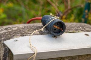 svart elektrisk plugg med en röd sladd bunden till den foto