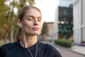 en konditionsmedveten kvinna engagerad i en joggning session på en stad väg, omgiven förbi urban arkitektur och de värma glöd av solnedgång. de scen slingor en livsstil av hälsa, vitalitet, och urban levande. foto