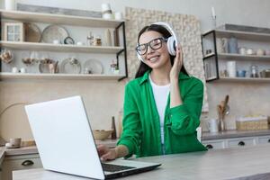 attraktiv ung kvinna arbetssätt med bärbar dator och lyssnande musik på Hem. foto