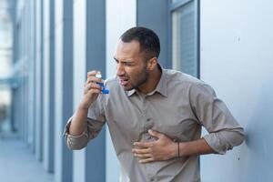 ett ge sig på av astma, allergier. en ung man använder sig av ett inhalator, har bröst smärta och korthet av andetag foto