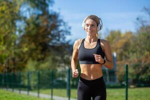 aktiva ung kvinna joggning utomhus bär sportkläder och hörlurar, utsöndrar kondition och hälsa. foto