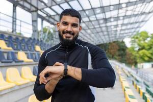 leende idrottare kontroll tid på smart klocka på stadion foto