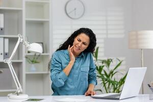 en professionell kvinna upplevelser plötslig tandvärk på henne arbetsplats, illustrerar allmänning hälsa frågor under upptagen arbetsdagar. foto