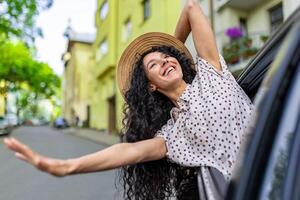 ung flicka reser förbi bil, latinamerikan kvinna med lockigt hår ser ut de fönster, njuter semester och resa. foto