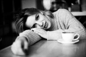 avslappnad kvinna med kaffe. kvinna lögner på tabell, leende, avslappnad. kaffe kopp sitter i främre av henne. tillfällig, mysigt scen. njuter en ögonblick av avslappning. värma atmosfär. foto
