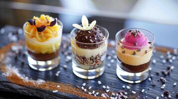 en trio av miniatyr- desserter Inklusive en miniatyr- creme brulee choklad tryffel och passionen frukt mousse i delikat skott glasögon foto