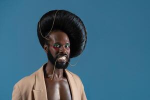 porträtt av svart Gay man bär peruk och jacka i blå studio foto