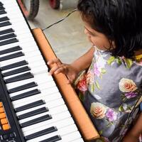 asiatisk söt flicka spelar de synthesizer eller piano. söt liten unge inlärning på vilket sätt till spela piano. barnets händer på de tangentbord inomhus. foto