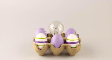 för påsk, där är lila påsk ägg och en volfram ljus Glödlampa i en kartong ägg behållare. konceptuell kreativ aning och innovation. de begrepp av påsk idéer foto