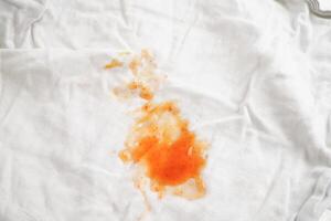 smutsig tomat sås färga eller ketchup på trasa till tvätta med tvättning pulver, rengöring hushållsarbete begrepp. foto