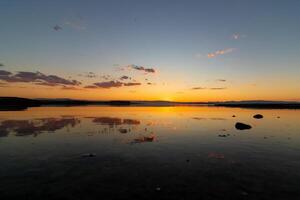 solnedgång eller soluppgång se över de sjö med delvis molnig himmel foto