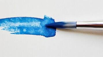 stänga upp av en blå vattenfärg paintbrush dricks på en vit bakgrund foto