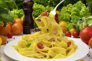 tallrik av italiensk pasta, fettuccine på gaffel med tomater och basilika foto