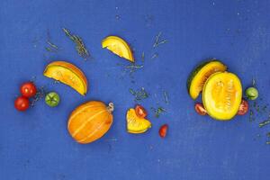 mat begrepp bakgrund. pumpa, tomater och timjan på blå tabell. topp se foto