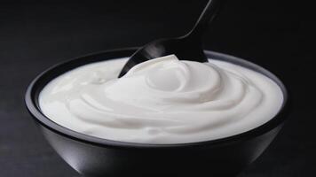 skål av sur grädde på svart bakgrund, grekisk yoghurt foto