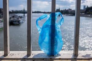 blå plast väska hängande på de räcke av Elizabeth bro över donau flod i budapest. sopor i de stad. miljö- förorening begrepp. ekologisk katastrof, katastrof. selektiv fokus foto