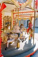 liten flickor rida en leksak hästar på en färgrik karusell. tillbaka se foto
