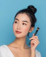 porträtt av en skön leende asiatisk kvinna med en slät och rena ansikte. hud vård reklam begrepp för ungdom med ljus aqua blå bakgrund. foto