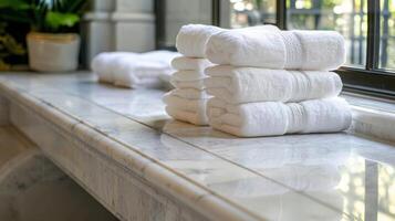 plysch överdimensionerad handdukar ordentligt vikta på marmor bänkar för gäster till koppla av på. foto
