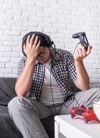 besviken ung man som spelar videospel hemma foto