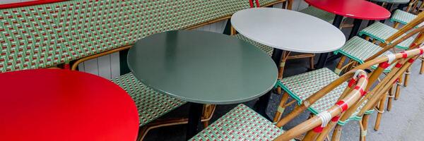 färgrik parisian Kafé terrass med tömma röd, vit, och grön stolar och bord, stimulerande av europeisk kultur och utomhus- dining utrymmen foto