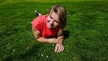 glad barn i en röd t skjorta spelar på en frodig grön äng på en solig dag, fångande de väsen av sommar roligt och barndom oskuld foto