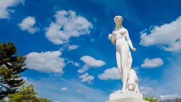 elegant klassisk marmor staty under en klar blå himmel med fluffig vit moln, fångad i paris, Frankrike, på april 14:e, 2024, idealisk för konst och resa teman foto