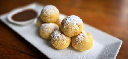 hemlagad dutch poffertjes mini pannkakor med glasyr pulveriserad socker och choklad fyllningar med ytterligare choklad sås foto