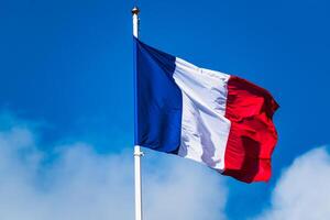 franska tricolor flagga fladdrande med stark vind och blå himmel foto