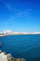 cadiz vägbank panorama med katedral de santa cruz, stor vågbrytare stenar och atlanten hav. havet se av cadiz. se av de promenad kaj andalusien område, Spanien foto