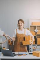 asiatisk sme företag kvinnor använda sig av bärbar dator dator kontroll kund beställa uppkopplad frakt lådor på Hem. startande små företag entreprenör sme frilans. uppkopplad företag, arbete på Hem begrepp. foto