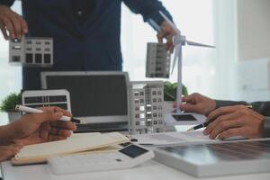 team av arkitekturer och affärsman är diskuterar och brainstorming på golv planen modifiering för verklig egendom hållbar investering och sol- energi hus utveckling projekt foto