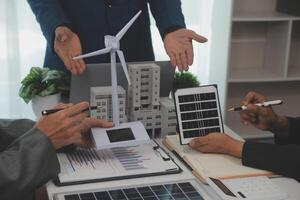 team av arkitekturer och affärsman är diskuterar och brainstorming på golv planen modifiering för verklig egendom hållbar investering och sol- energi hus utveckling projekt foto