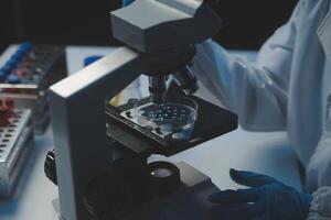 professionell kemist kvinna laboratorium använder sig av vetenskaplig mikroskop för vetenskap forskning, kemi forskare med mikrobiologi läkarbesök Utrustning teknologi till arbetssätt med medicin biologi experimentera foto