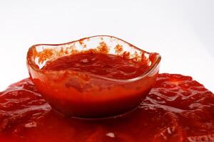 tomat sås . glas kopp med återstående ketchup och ketchup spillts runt om Det. foto