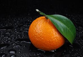 mogen saftig mandarin på en svart bakgrund med vatten droppar. foto